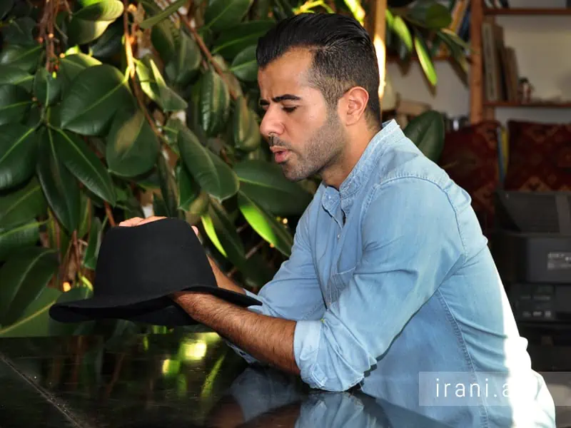 مردی با کلاه در گالری عکس مرتضی توکلی در گفتگو با یکی از مجلات ایرانی به تصویر کشیده شده است.