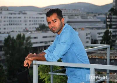مردی با پیراهن آبی که به نرده تکیه داده بود در مصاحبه با یک مجله ایرانی.